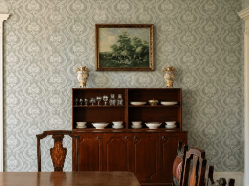 Salle à manger de South Hill House avec papier peint à motifs damassés, cabinet en bois présentant de la porcelaine, peinture de paysage encadrée et