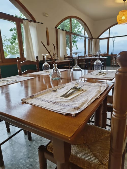 Elegante comedor del Hotel El Balco del Priorat con mesas de madera, cubiertas y ventanales panorámicos con vistas