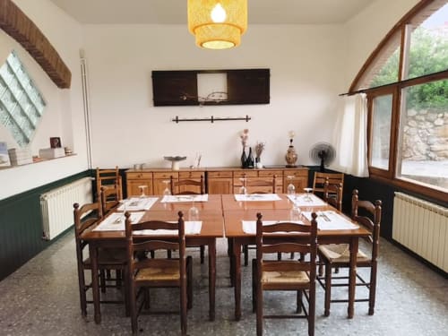 Comedor del Hotel El Balco del Priorat en Tarragona con mesa de madera, sillas y decoración rústica