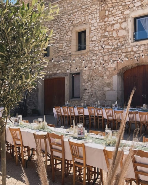 Salle à manger en terrasse au Domaine Maison Girardon avec chaises en bois, architecture en pierre et décor rustique à La Roche sur Yon