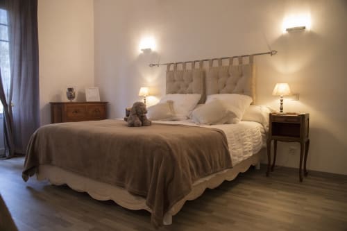 Chambre élégante au Domaine de Castagnère avec tête de lit capitonnée, éclairage chaleureux et mobilier en bois à Lanne-Soubiran