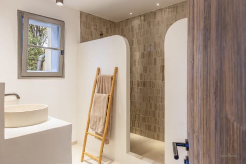 Salle de bain moderne de la villa Constance à La Conciergerie du Cap Corse avec cloison blanche courbe, porte-serviettes en échelle en bois et