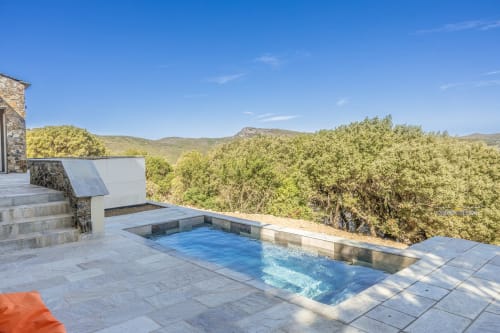 Terrasse de piscine d'une villa de luxe avec vue sur les collines méditerranéennes, Ersa Corse, patio en pierre et panoramas montagneux