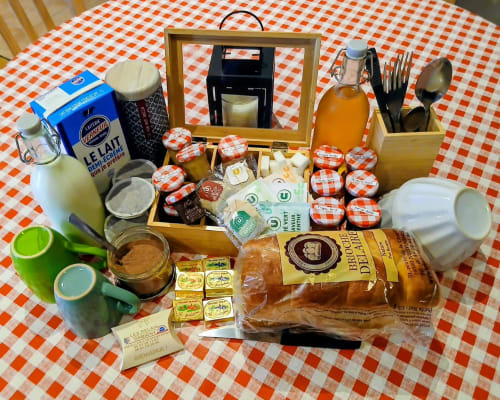 Panier de bienvenue à Les Relais-Orbigny avec lait, pain, confitures, beurre et provisions locales sur nappe à carreaux