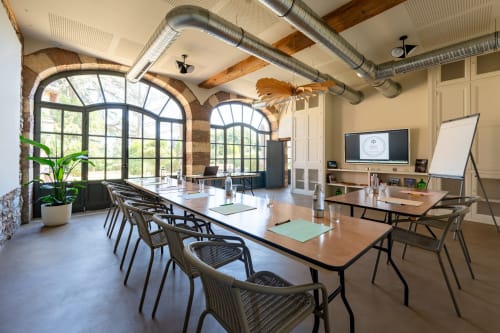 Modern conference room at La Maison & l'Orangerie, Saint-Jean-des-Vignes with long table, arched windows and industrial
