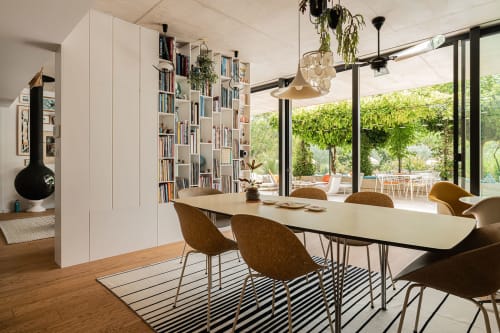 Salle à manger contemporaine de la Maison Jalon B&B à Aix-en-Provence avec table, chaises beiges, bibliothèques et vue sur le jardin.