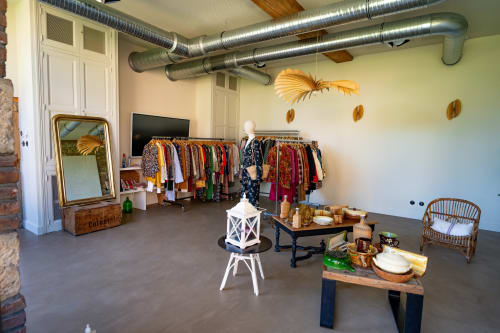 Boutique retail shop at La Maison & l'Orangerie displaying colorful clothing racks, decorative items, and rustic furniture in