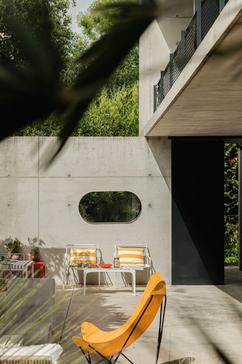 Terrasse ensoleillée de la villa Maison Jalon à Aix-en-Provence avec transats rayés, fauteuil jaune et murs en béton