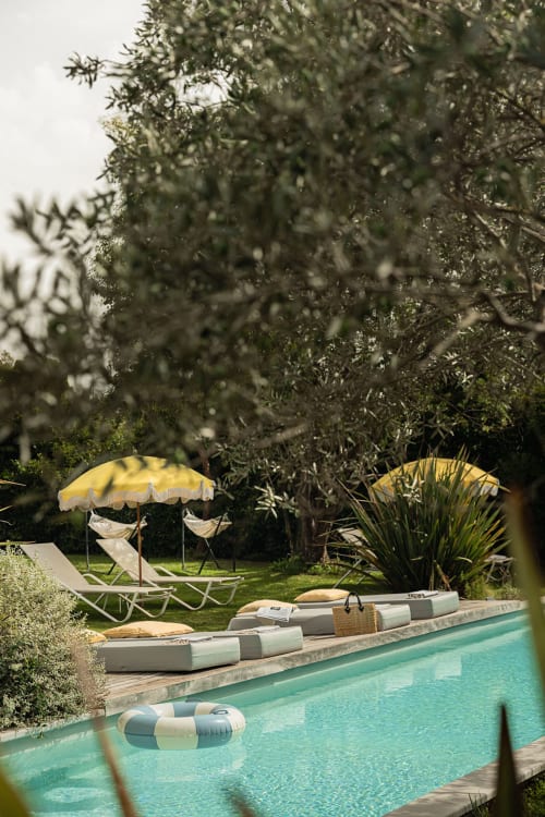 Piscine turquoise de la villa Maison Jalon à Aix-en-Provence avec transats, parasol jaune et jardin luxuriant
