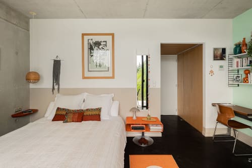 Chambre moderne à la villa Maison Jalon à Aix-en-Provence avec lit blanc, accents orange, mobilier en bois et vert menthe