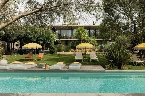 Piscine de la villa Maison Jalon avec parasols jaunes, transats et maison contemporaine à Aix-en-Provence