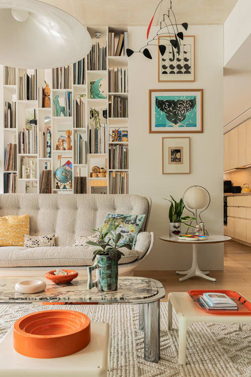 Salon moderne de la villa Maison Jalon à Aix-en-Provence avec canapé crème, étagères curatées et touches d'orange