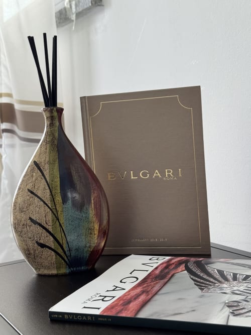 Elegante diffusore Bulgari e libri esposti sulla scrivania della suite premium di Aurora View Resort in Italia