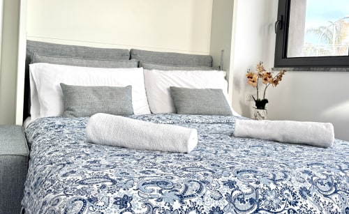 Letto matrimoniale di lusso presso Aurora View Resort con biancheria blu decorata, testata grigia, cuscini bianchi e vista mare