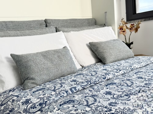Camera da letto premium presso Aurora View Resort con testata grigia, cuscini bianchi, biancheria blu con motivi e pianta di orchidea