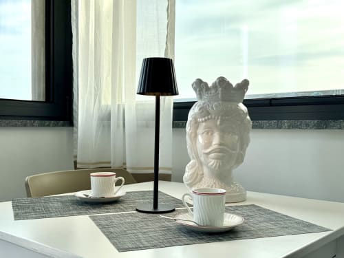Scrivania elegante con busto scultoreo bianco, tazze di caffè e lampada da tavolo con vista sul mare ad Aurora View Resort