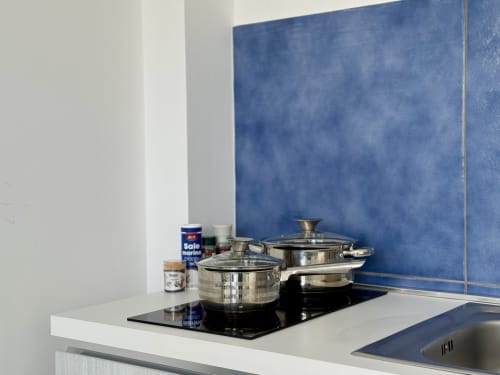 Cucina moderna del resort Aurora View con pentolame in acciaio inossidabile su piano cottura nero e rivestimento blu