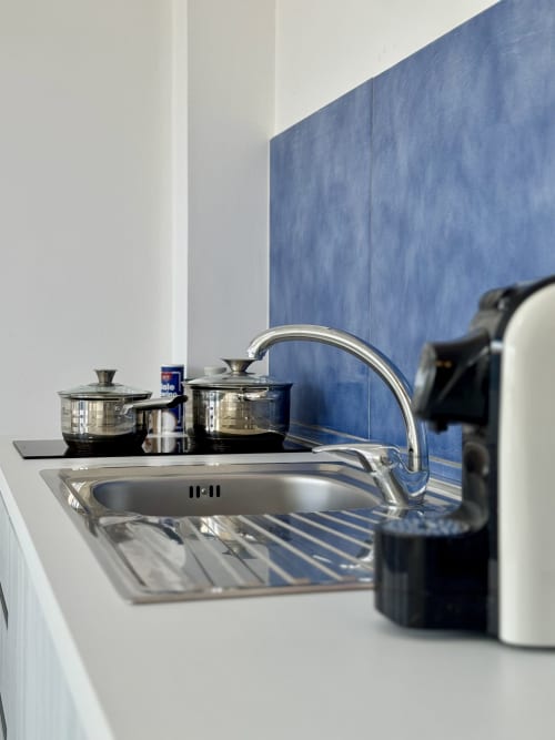 Angolo cottura moderno con lavello in acciaio inox, rubinetto, batterie di cucina e piastrelle blu a Aurora View Resort, Italia