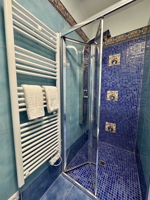 Bagno moderno al Aurora View Resort con doccia in piastrelle blu, scaldasalviette bianco e dettagli decorativi