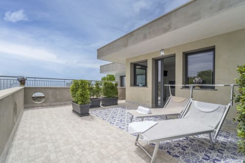 Ampia terrazza dell'Aurora View Resort con lettini, piante in vaso e vista mare in Italia