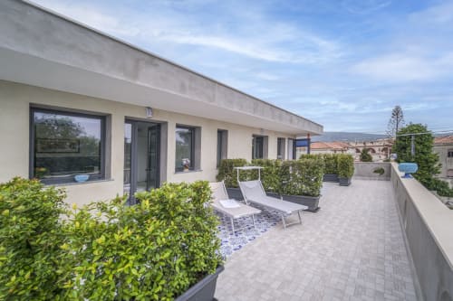 Ampia terrazza panoramica ad Aurora View Resort con lettini, piante in vaso e vista sul mare sul borgo costiero italiano