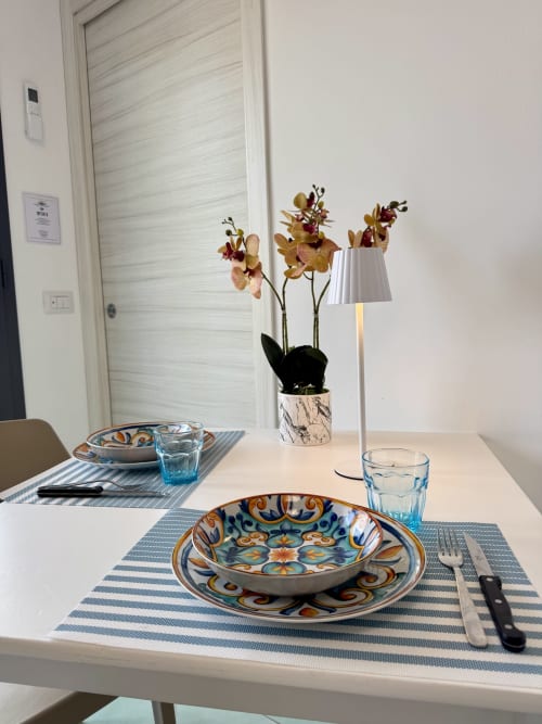 Elegante allestimento nella sala da pranzo dell'Aurora View Resort con piatti decorativi, orchidee e arredi moderni nella camera con vista sull'Etna