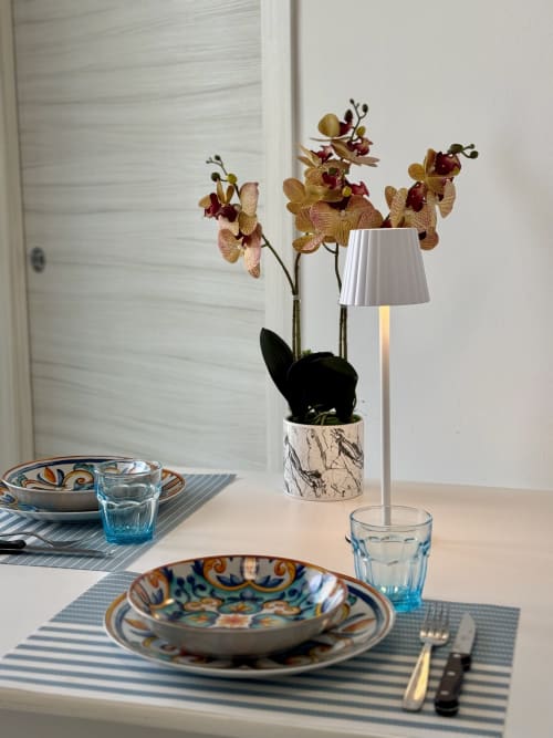 Elegante tavolo all'Aurora View Resort con orchidee, tovaglietta rigata, piatti decorativi e lampada moderna in stile italiano