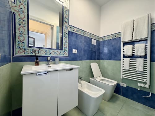 Bagno moderno all'Aurora View Resort con piastrelle blu e verdi, sanitari bianchi, scaldasalviette e dettagli decorativi