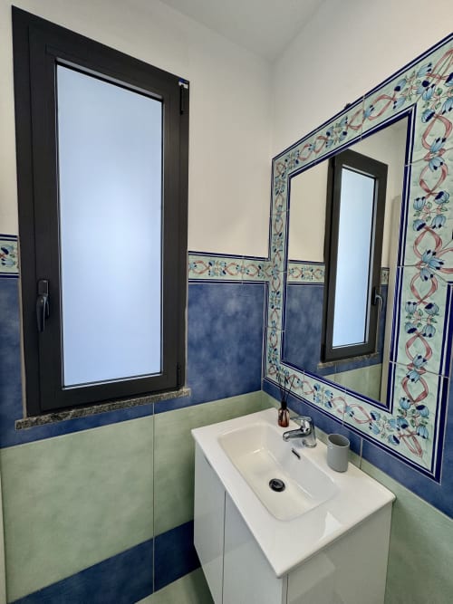 Bagno moderno all'Aurora View Resort con doppio lavabo, dettagli decorativi in azzurro, e ampi specchi sulla costa italiana
