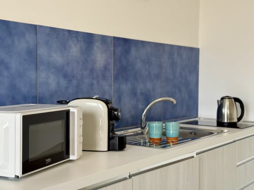 Piano cucina moderno di Aurora View Resort con microonde, macchinetta del caffè, bollitore e rivestimento di piastrelle blu