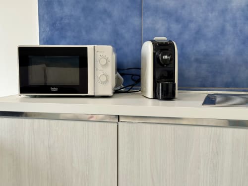 Elettrodomestici della cucina ad Aurora View Resort: microonde, bollitore e caffettiera su bancone bianco con parete blu