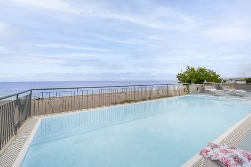 Piscina a sfioro panoramica con vista mare a Aurora View Resort, villa costiera con lettini e balcone con vista sull'Etna