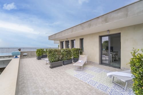 Terrazza premium di Aurora View Resort con vista mare, lettini, piante in vaso e eleganti porte in vetro con vista sull'Etna