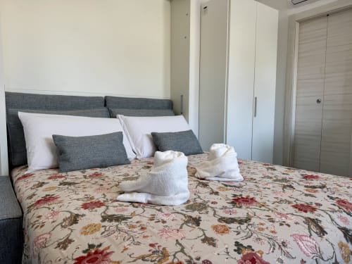 Camera da letto doppia deluxe presso Aurora View Resort con biancheria floreale, testata grigia, cuscini bianchi e asciugamani bianchi