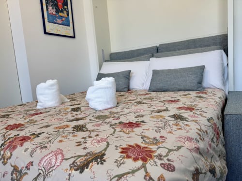Camera deluxe di Aurora View Resort con biancheria floreale, testata grigia, cuscini bianchi e asciugamani piegati