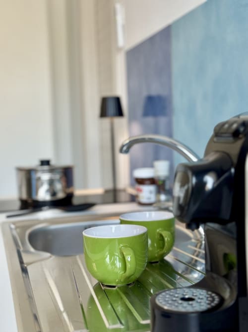 Tazze verdi sul bancone della kitchenette in camera hotel Aurora View Resort con macchina da caffè e lavandino
