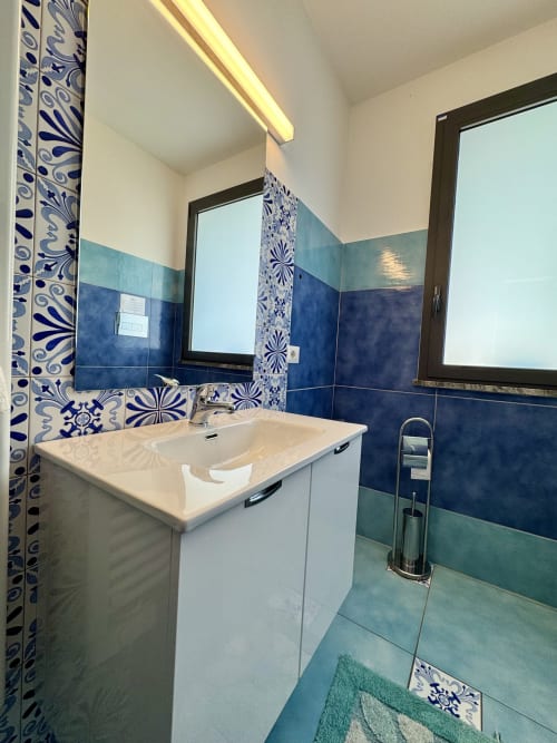 Bagno moderno al Aurora View Resort con piastrelle blu e bianche, vanity bianca e dettagli decorativi in stile portoghese