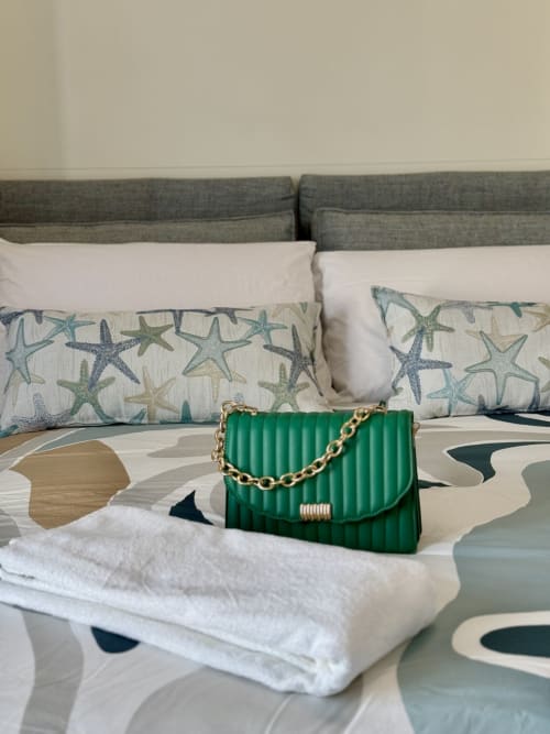 Borsa trapuntata verde sul letto con cuscini a forma di stella marina presso l'Aurora View Resort, boutique hotel italiano