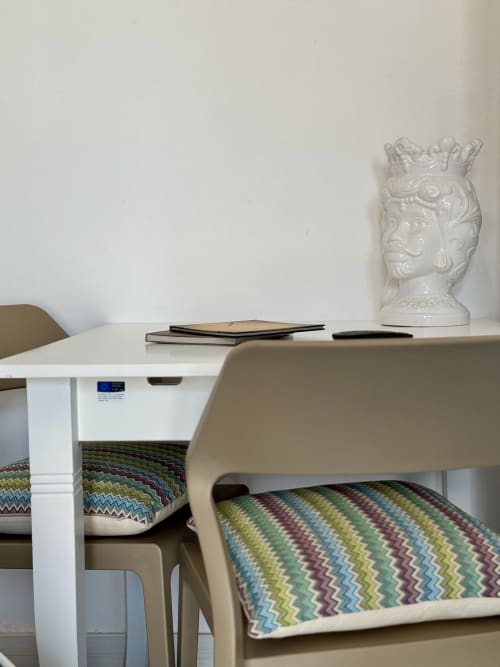 Scrivania moderna nella camera dell'Aurora View Resort con tavolo bianco, sedie beige e cuscini con motivi colorati