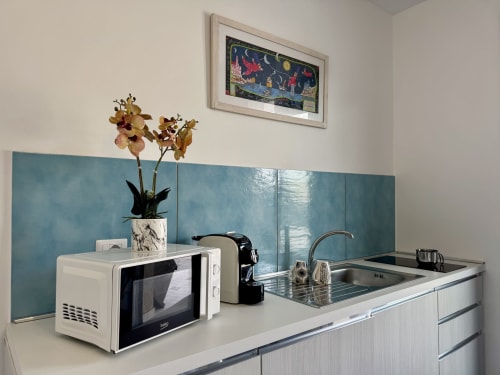 Moderna cucina presso l'Aurora View Resort con microonde, lavello e rivestimento in tonalità teal, nella camera dell'hotel italiano