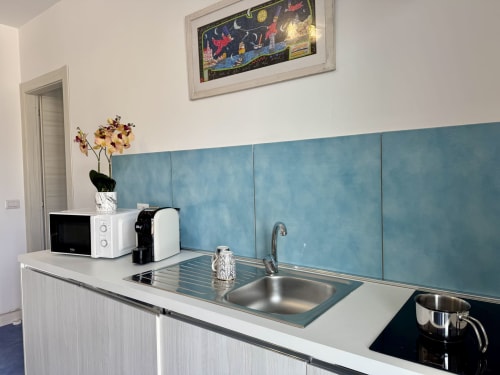 Cucina moderna presso Aurora View Resort con rivestimento blu, lavello in acciaio, microonde e macchina da caffè