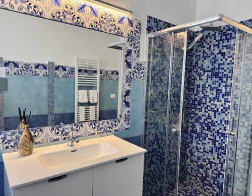 Bagno moderno presso Aurora View Resort con doccia in mosaico blu, piastrelle ornamentali, vanità bianca e scaldasalviette