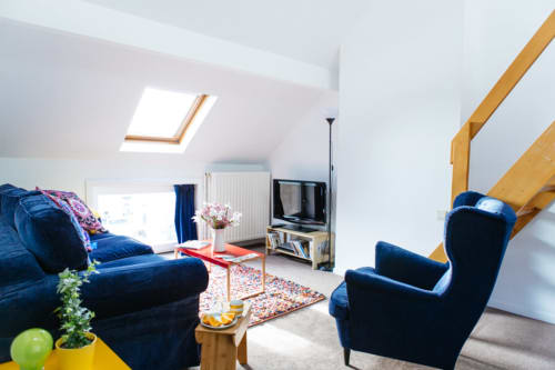 Séjour du studio duplex avec mobilier bleu et poutres en bois au B&B Place Jourdan à Bruxelles