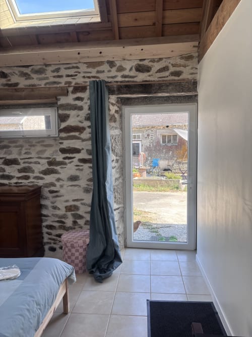 Chambre en pierre avec lit, porte-fenêtre donnant sur la cour aux Chambres De Napoléon, Lannedern