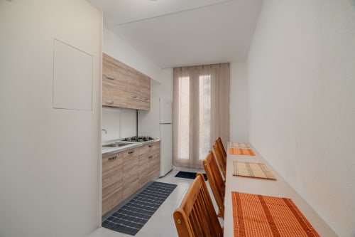 Cucina moderna con arredamenti in legno, tavolo da pranzo con sedie arancioni presso Short Let's Olbia