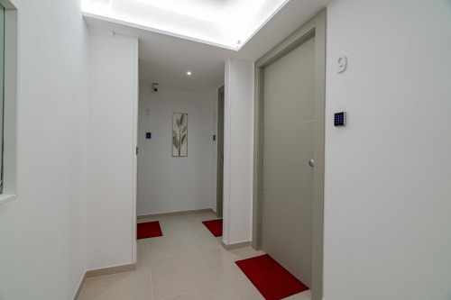 Modern apartment hallway at Short Let's Olbia with clean white walls, red welcome mats, and beige doors