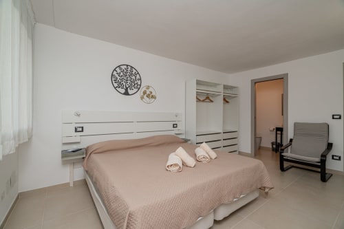 Modern bedroom at Short Let's Olbia hotel with queen bed, white wardrobe, and contemporary decor in Olbia, Italy
