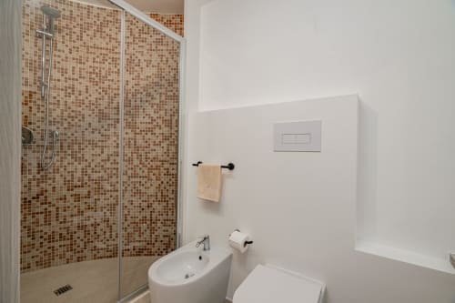 Modern bathroom at Short Let's Olbia with mosaic tile shower, white sink, and toilet in Olbia, Italy