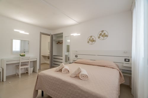 Modern bedroom at Short Let's Olbia with queen bed, en-suite bathroom, vanity desk, and neutral decor