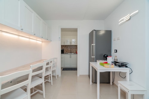 Modern kitchen and dining area at Short Let's Olbia with white cabinetry, stainless steel appliances, and bright ambient